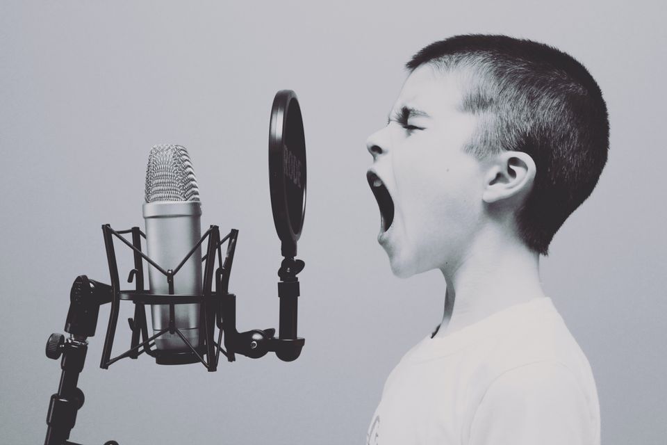 Black & white picture of a young male in a white t shirt, shouting into a microphone