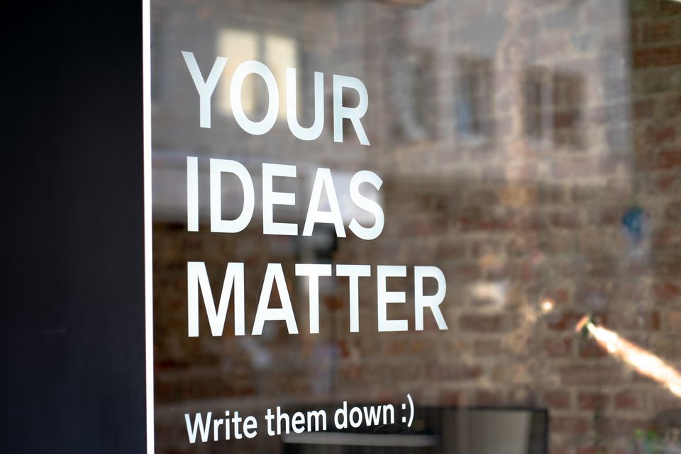 A sign on a window reads "Your ideas matter. Write them down" with a smiley face